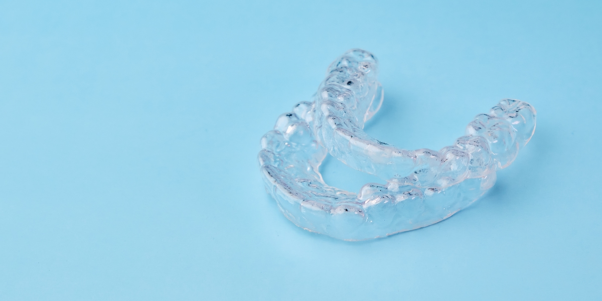 Close up invisible aligners on the blue background with copy space. Plastic braces dentistry retainers to straighten teeth.
